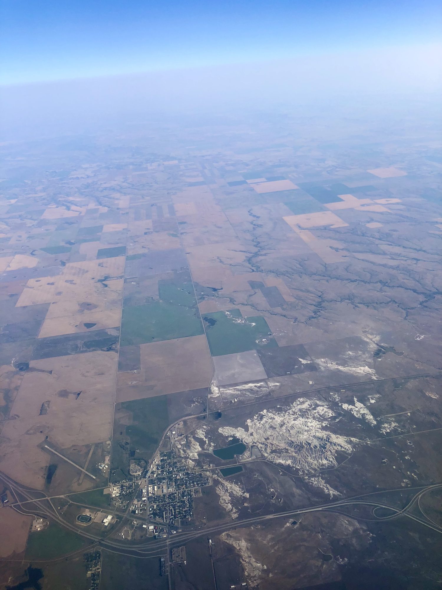 The first glimpse from the plane — a white-gray scar of Badlands breaking the farmland grid