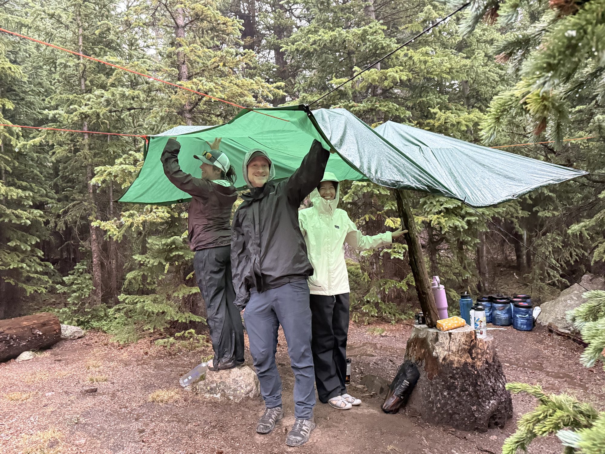 The rain tarp up over the kitchen, canisters below — round two of the team-building exercise.