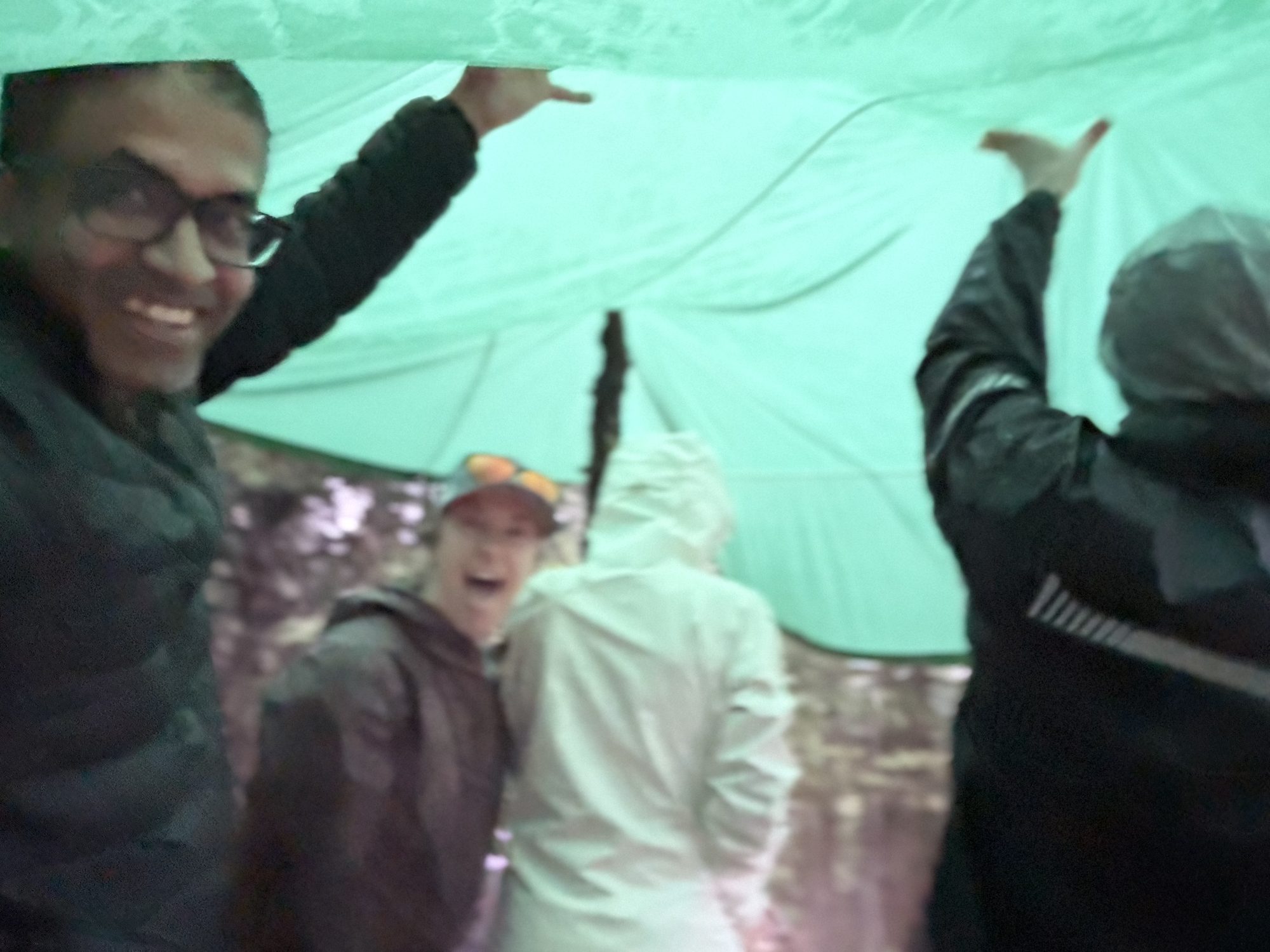 Under the green tarp in the hail at 11,000 feet, arms up and laughing